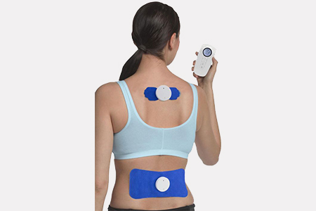 Woman facing away from the camera with a tens pad across her lower back and a tens pad across her up back covering just her area between her shoulder blades